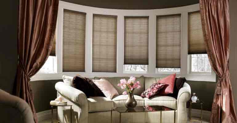 Vertical honeycomb shades in lounge bow window.